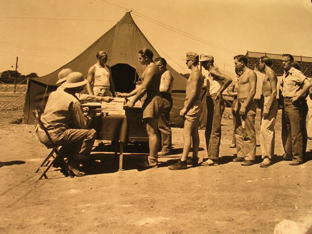 Photo of German prisoners of war at a camp near Owasso, Michigan, being paid with canteen checks by Camp Commander Captain Ohrt." 8-8-44 Photographer Sgt. S.L. Hertel. 